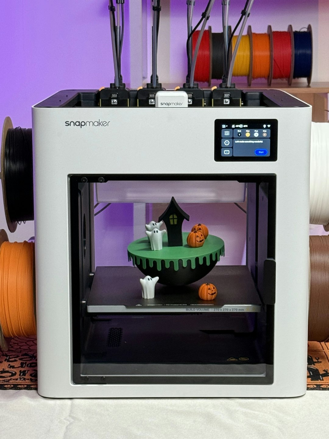 why-choose-us 3D model by @9percent. Snapmaker in a home maker setup, with filament spools on display and a Halloween 3D print showcased inside the enclosure.